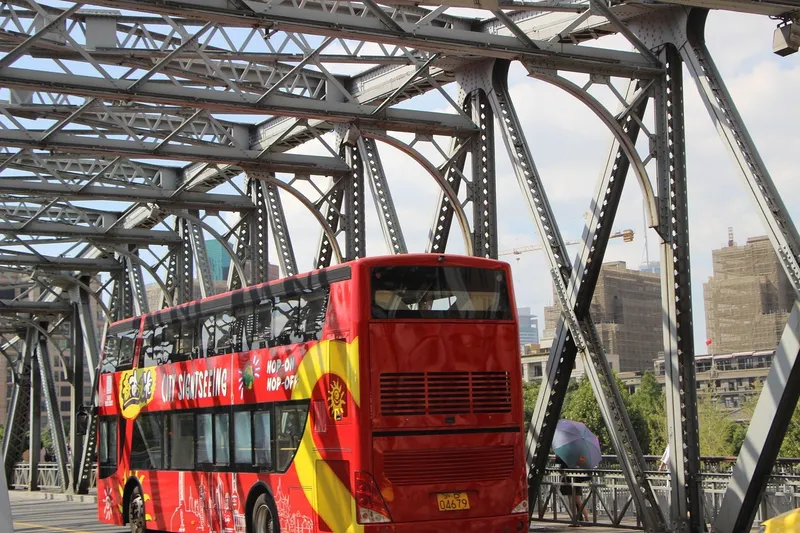 Open-top double-decker sightseeing bus crossing a city bridge