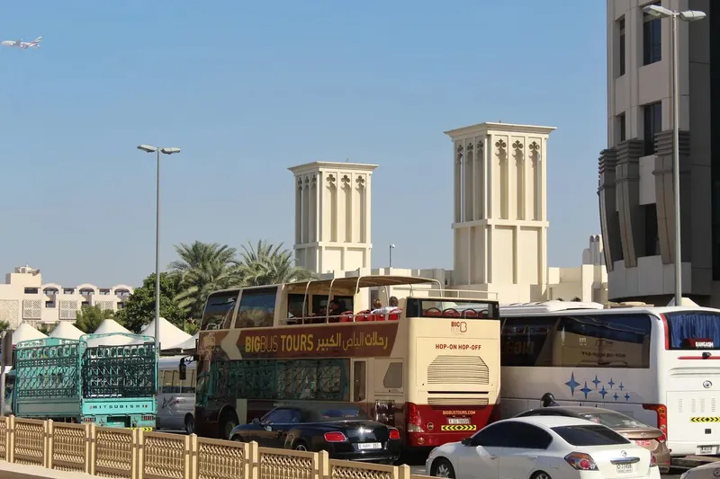 Open-top Big Bus Dubai sightseeing bus on street with wind towers