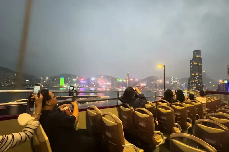 Open-top Big Bus Hong Kong double-decker with passengers viewing skyline at dusk