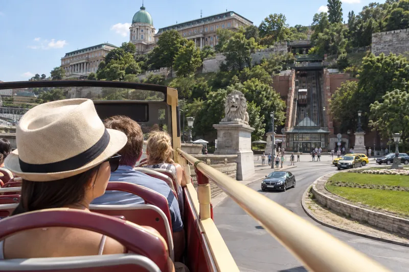 Open-top sightseeing bus passing Buda Castle and the funicular in Budapest