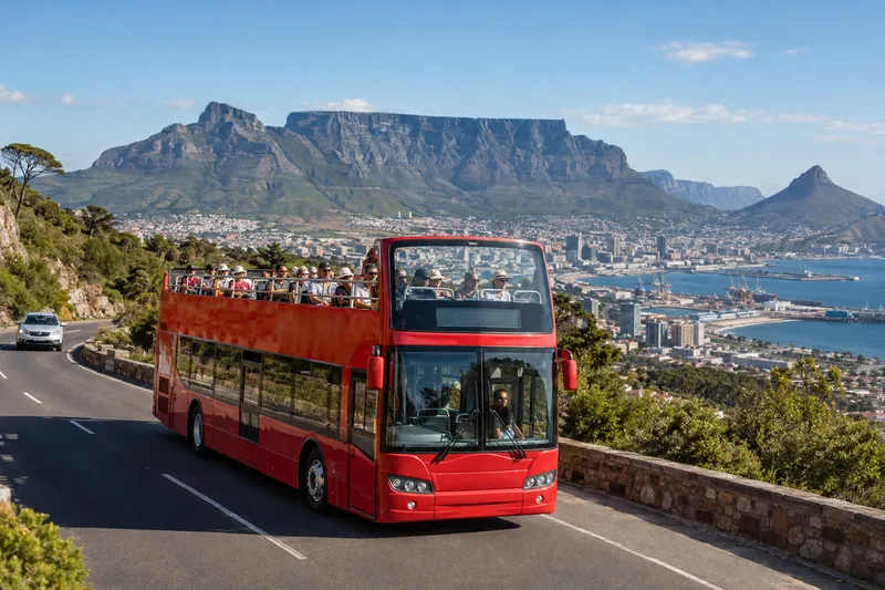 Red open-top sightseeing bus in Cape Town with Table Mountain in background
