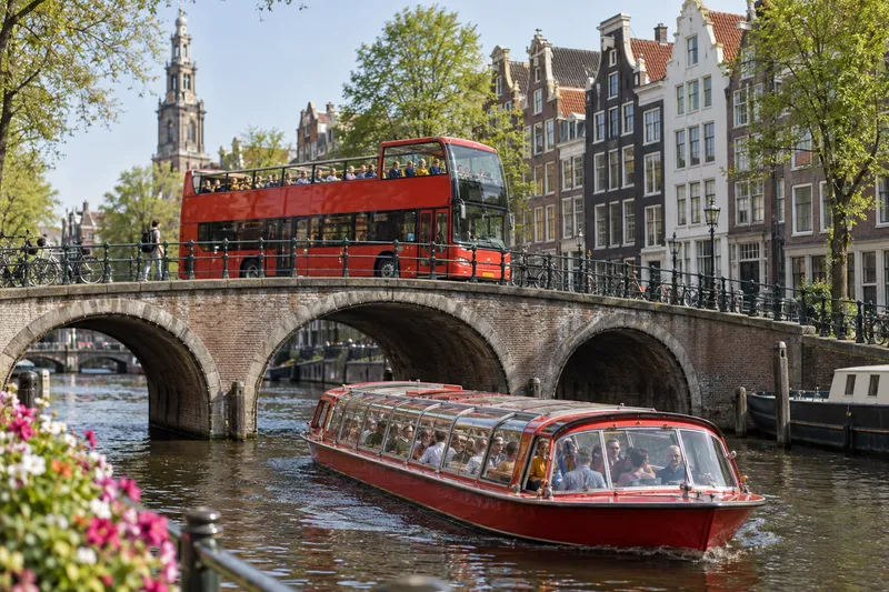 Red double-decker sightseeing bus and canal boat on Amsterdam canal