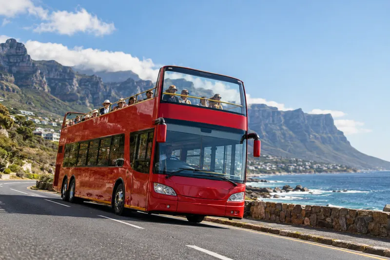 Open-top double-decker sightseeing bus in Cape Town with Table Mountain and coastal views