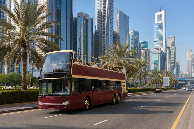 Double-decker sightseeing bus on a Dubai road with skyscrapers in the background