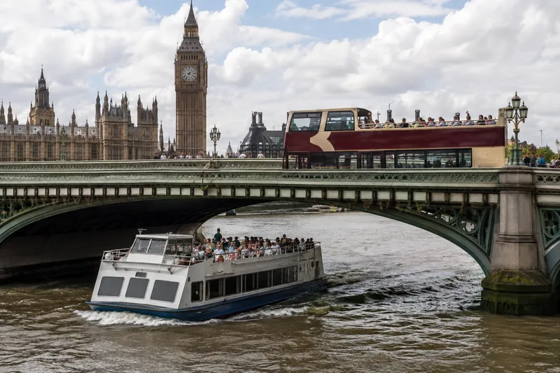 Open-top sightseeing bus and river cruise boat on the Thames by Westminster Bridge