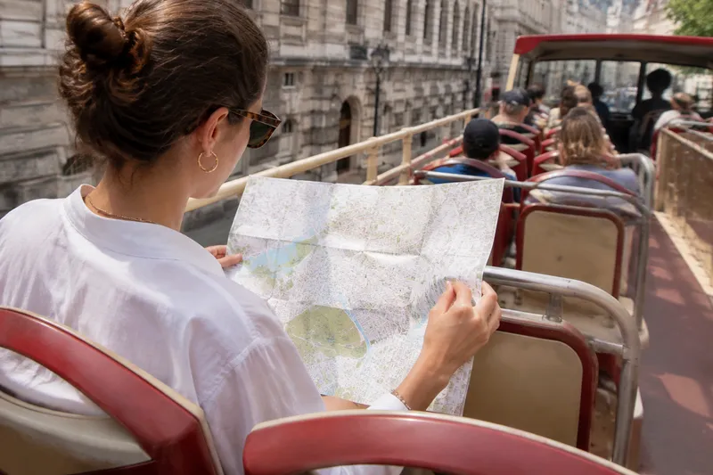 Passenger viewing a city map from an open-top sightseeing bus