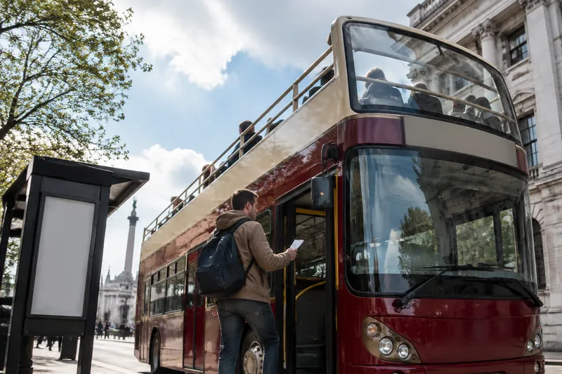 Passenger boarding an open-top double-decker sightseeing bus in the city