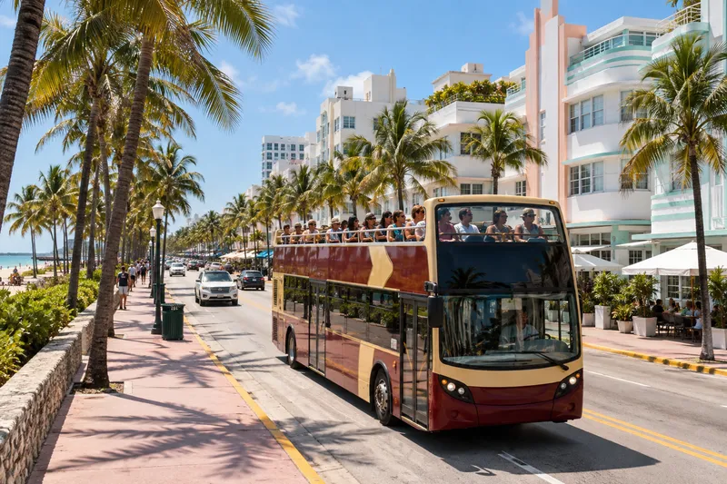 Open-top double-decker sightseeing bus on a palm-lined coastal avenue in Miami
