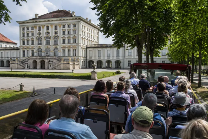 Open-top sightseeing bus touring central Munich with passengers and historic architecture