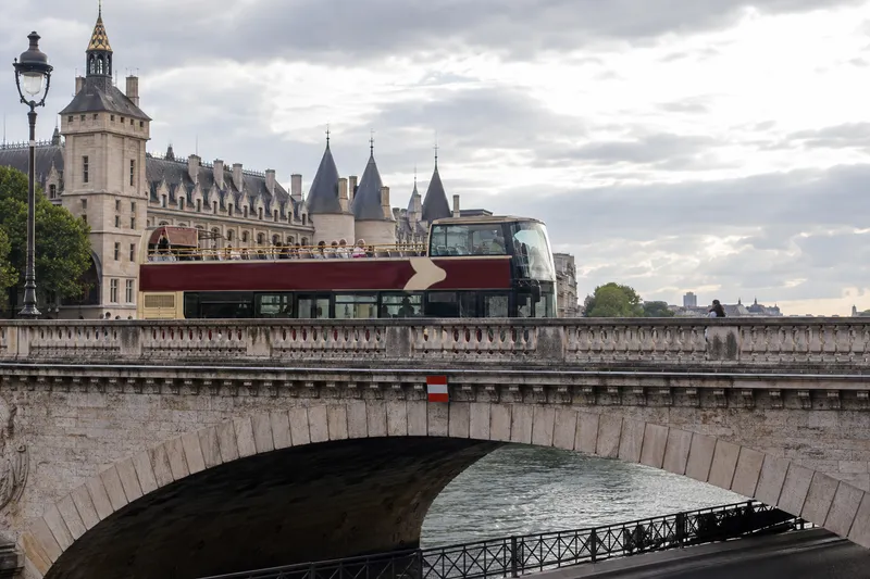 Double-decker sightseeing bus crossing a bridge over the Seine in Paris