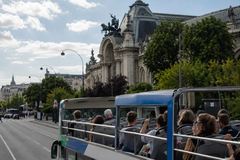 Open-top sightseeing bus passing historic European architecture in a city