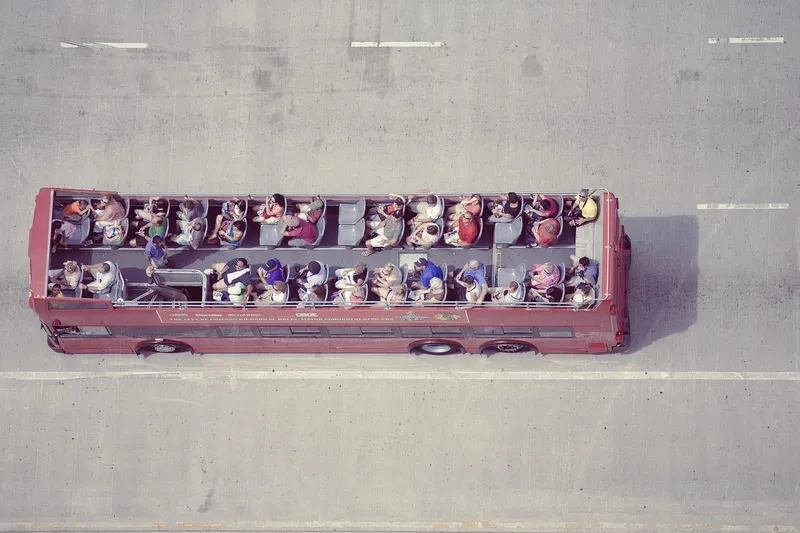 Open-top double-decker sightseeing bus carrying tourists along a city street
